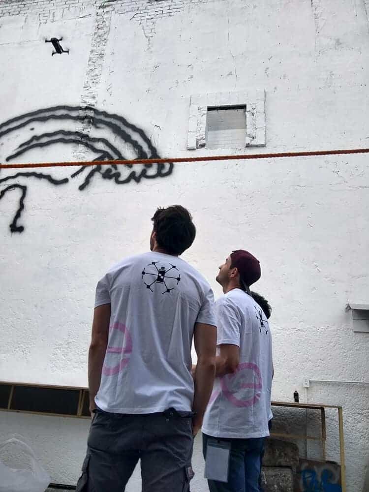 Two Men from The Drone Graffiti Project Team Looking at a Spray Drone in Action