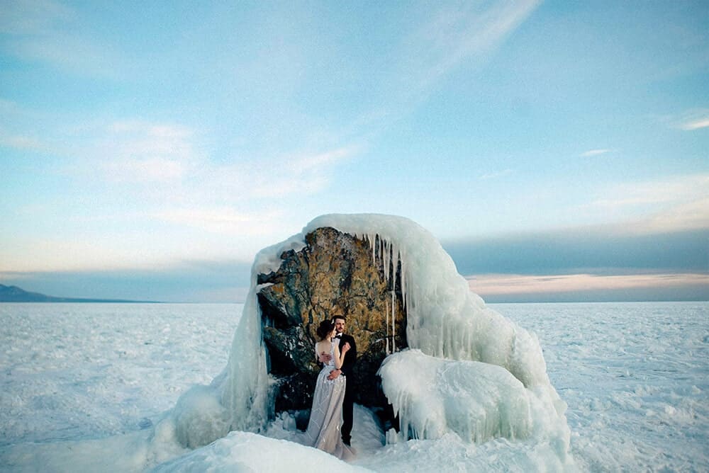 Newly married couple posing in front of ice rock